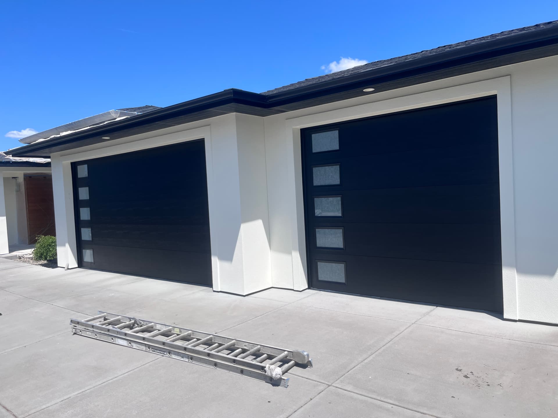 Completed home exterior with black garage doors and crisp white trim painted by Molina Bro's