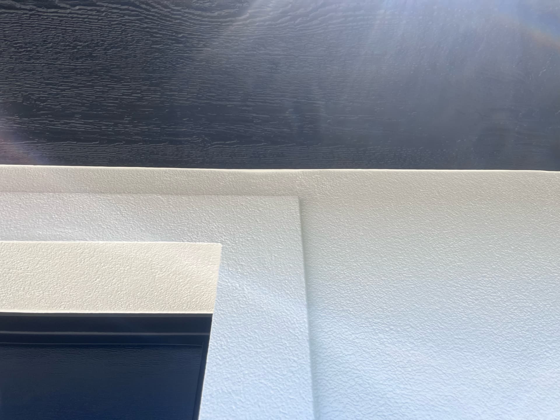 Close-up of razor-sharp trim edge against dark painted siding